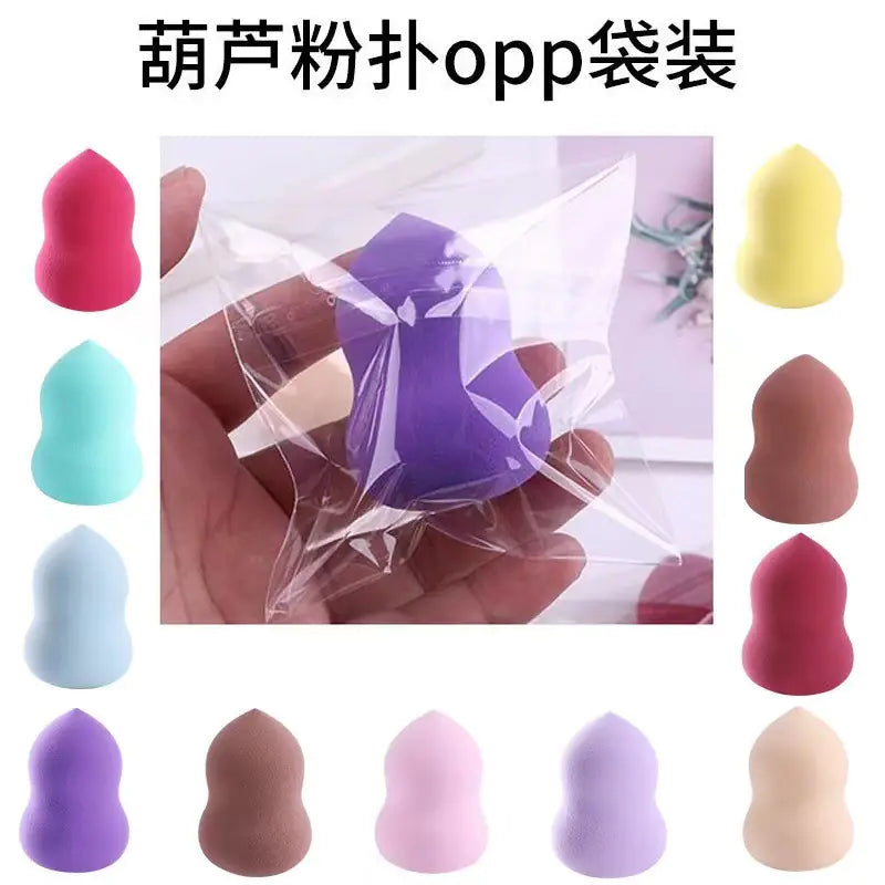 Makeup sponges in various colors with a hand holding one, surrounded by additional sponges on a white background.