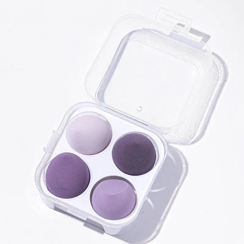Set of purple makeup sponges in a clear case on a white background