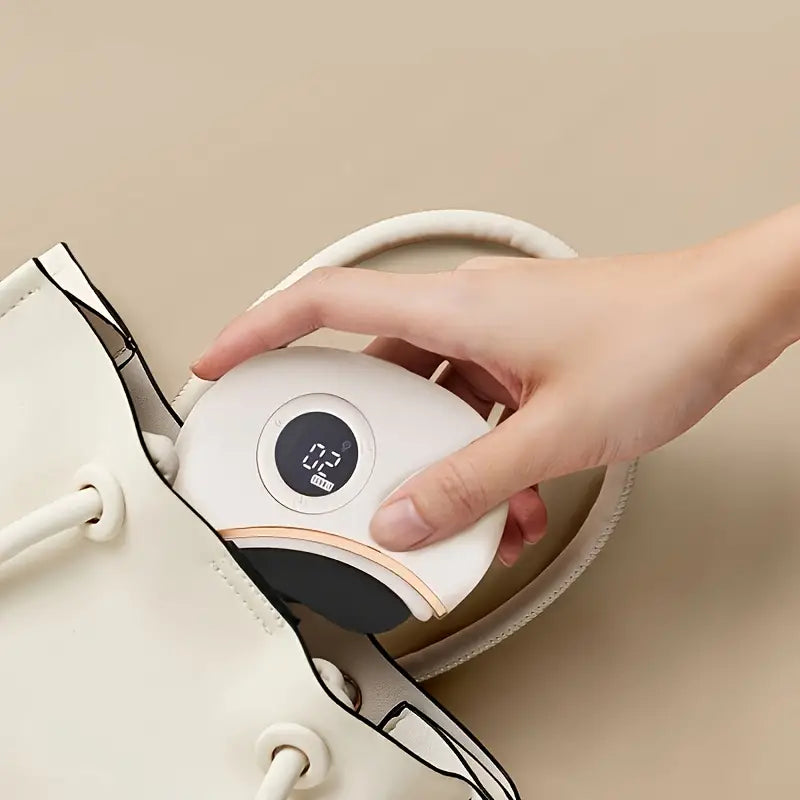 Hand holding a small white gua sha device with a digital display against a beige background