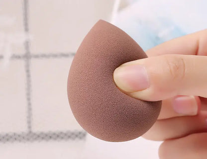 Brown makeup sponge held by a hand with a blurred background