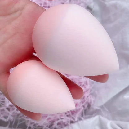 Two white silicone breast forms held by a hand against a blurred background.