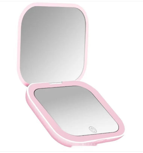 Pink compact mirror with a light on a white background