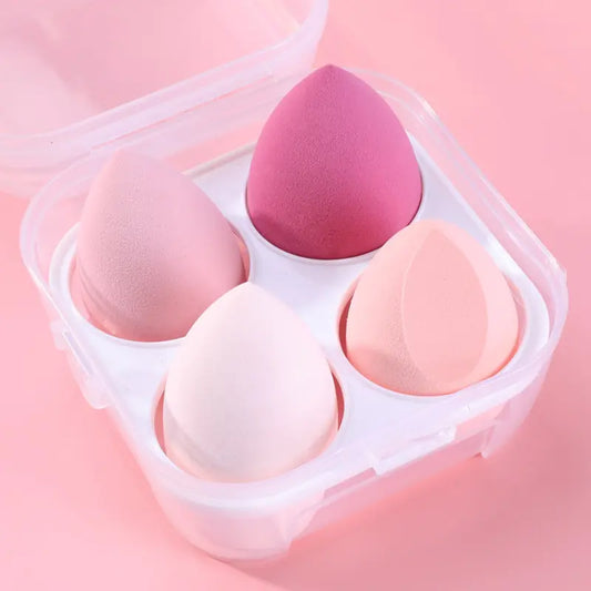 Set of pink and white makeup sponges in a clear container on a pink background