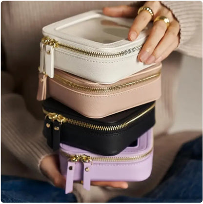 Stack of small, rectangular bags with gold zippers held by a person.