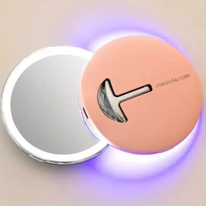 LED Compact folding mirror and silver handle on a beige background