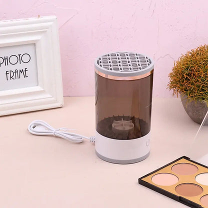 Small cylindrical device with a white base and transparent top on a pink surface with a photo frame and plant in the background.