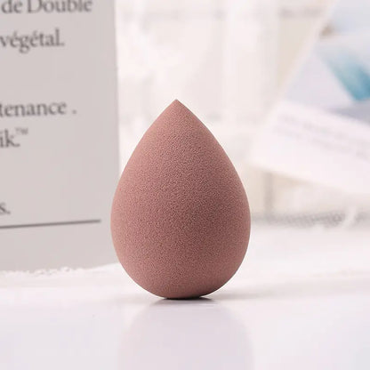 Coffee-colored makeup sponge on a white surface with blurred text in the background