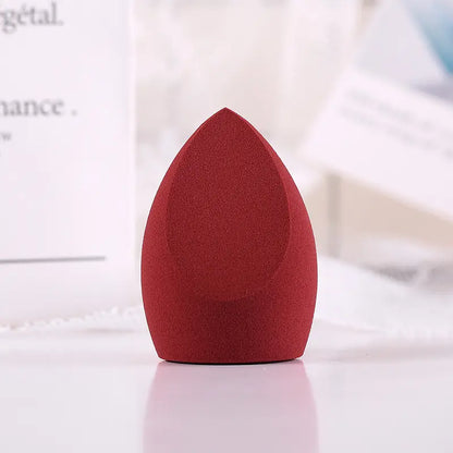 Red makeup sponge on a white surface with a blurred background