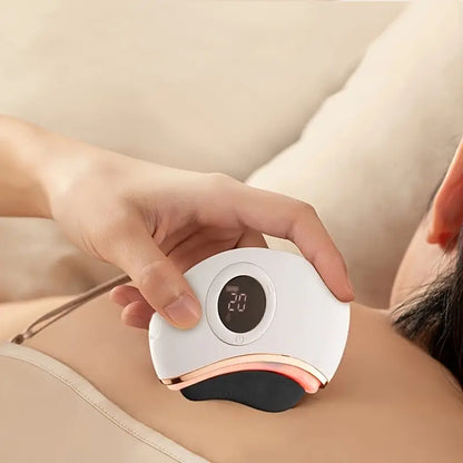 Person using a handheld electronic gua sha device on their shoulder with a blurred background