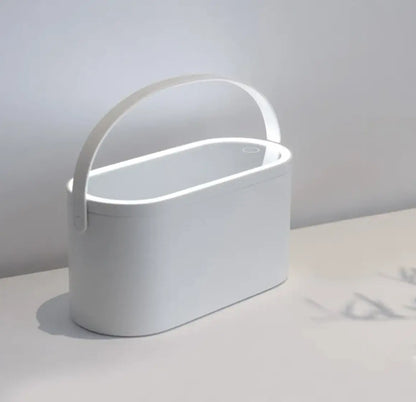 White cylindrical container with handle on a light gray surface