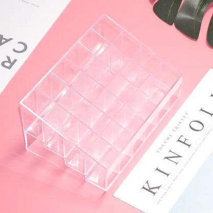 Clear acrylic cosmetic organizer on a pink surface with a magazine underneath