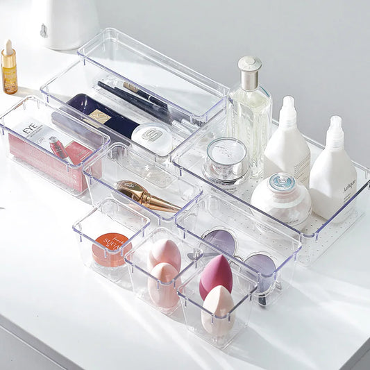 Clear acrylic cosmetic organizer with various beauty products on a white surface