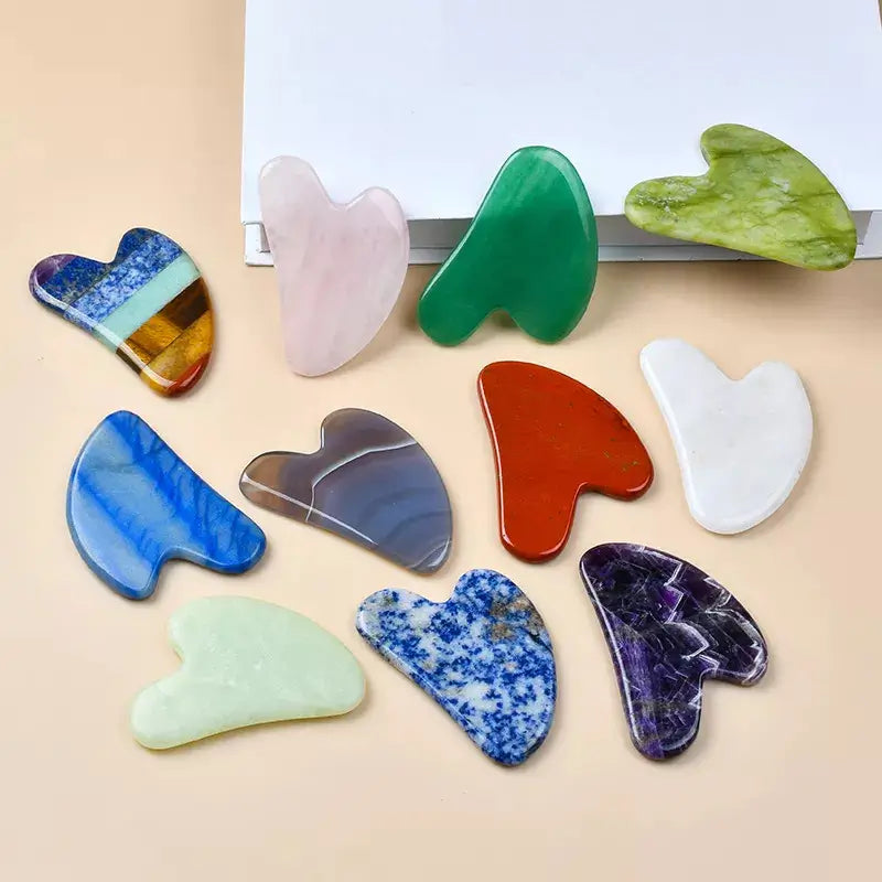 Collection of colorful gua sha tools on a beige background