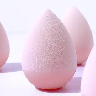 Close-up of pink makeup sponges on a white background