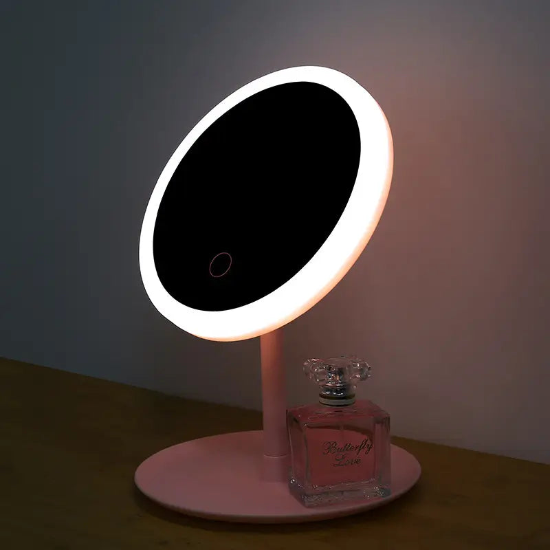 Makeup mirror with LED lights on a stand next to a perfume bottle.