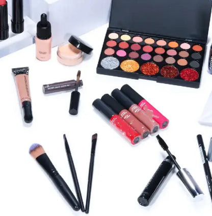 Collection of makeup products including lipsticks, eyeshadow palette, and brushes on a white background