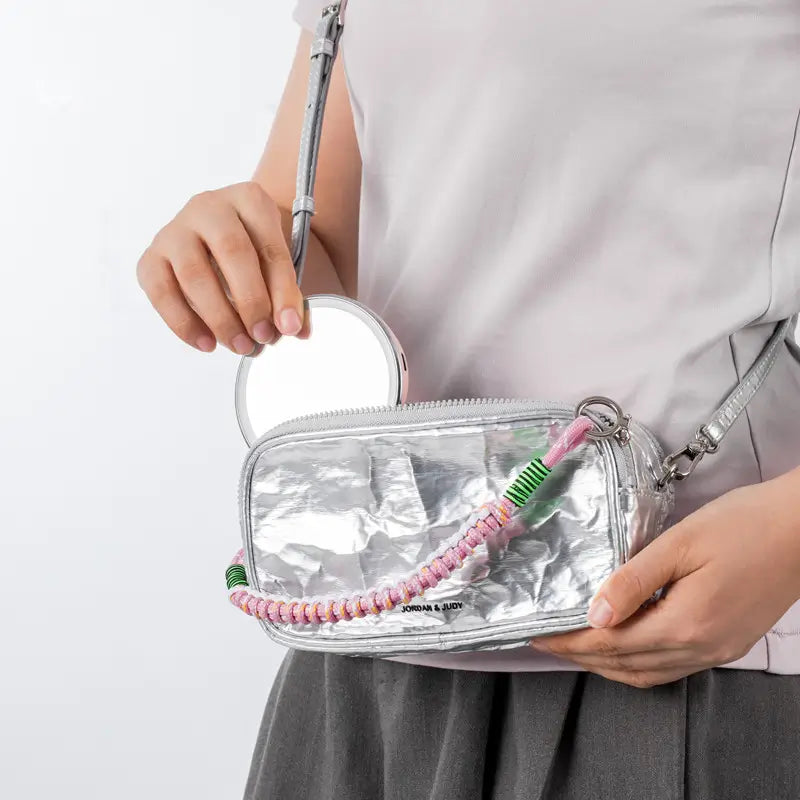 Clear pouch with colorful beaded strap held by a person on a white background